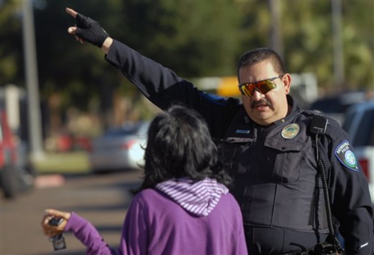 A Brownsville Police officer directs a parent to a building at Dean Porter Park in Brownsville,Texas, Wednesday, Jan. 4,2012. The park is across the street from Cummings Middle School, where a 15-year-old student was shot and killed by Brownsville police at the school after he was seen brandishing a weapon inside the school. (AP Photo/The Brownsville Herald, Brad Doherty)